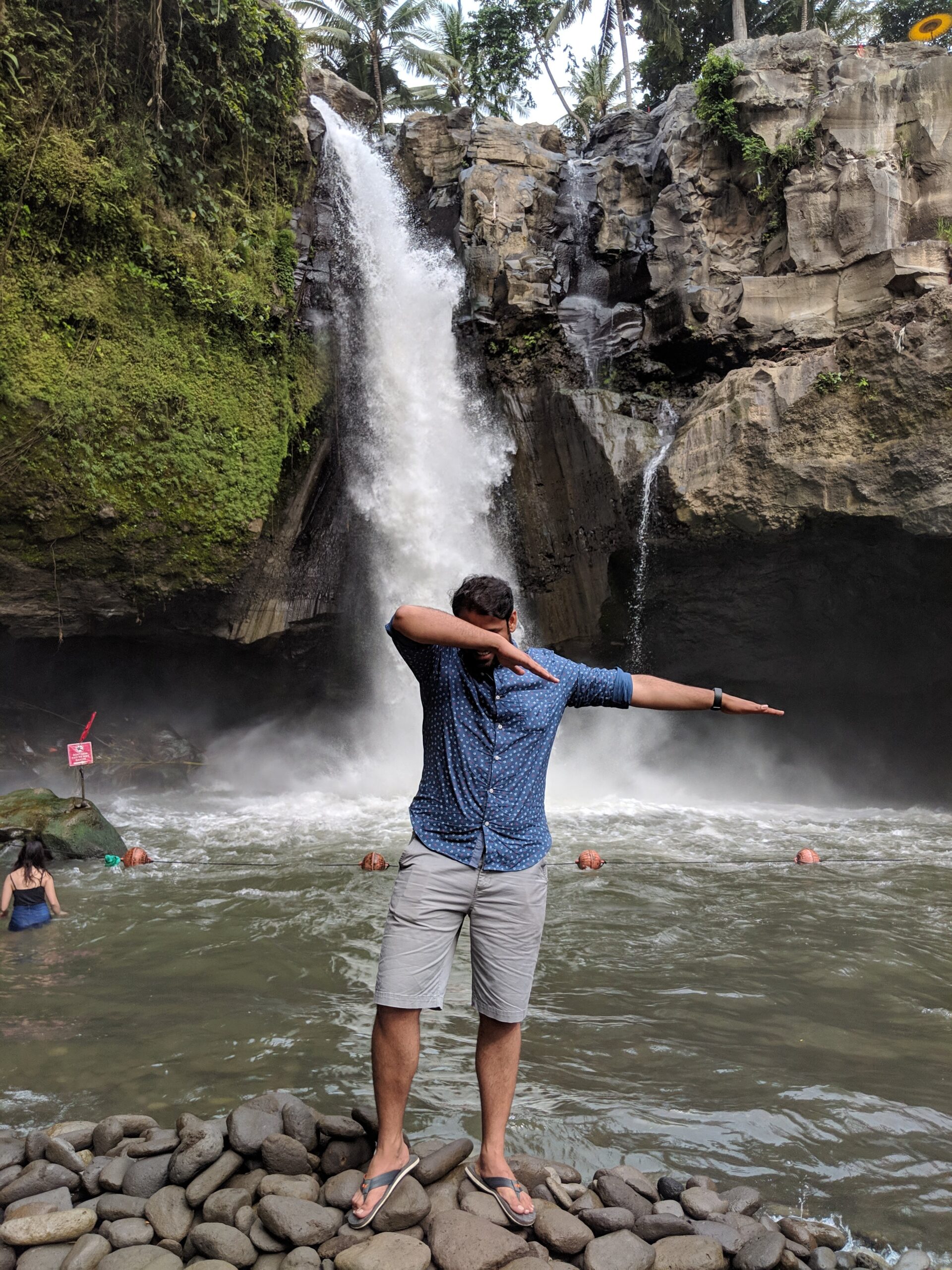 Kunal Bodke, photo in front of a waterfall. Kunal is posing in a dabbing dance style.